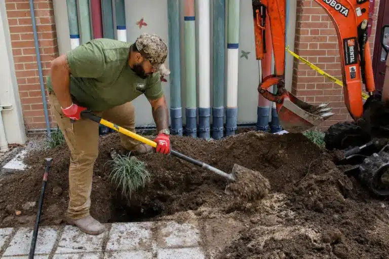 Worker digging beside the building’s utility pipes